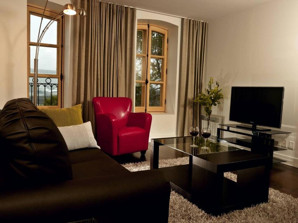 a living room with a couch and a red chair at Les Immeubles Charlevoix - Le 1176 in Quebec City