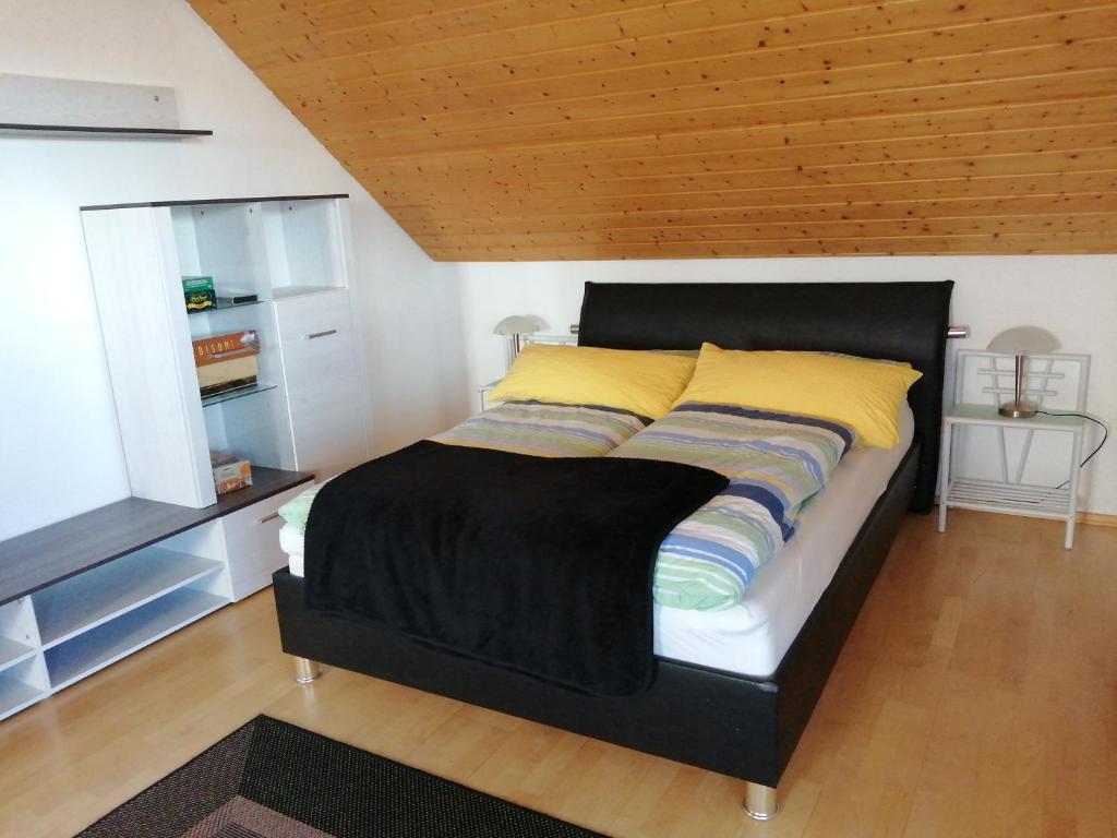 a bed with a black headboard and yellow pillows at FeWoDeg in Deggendorf