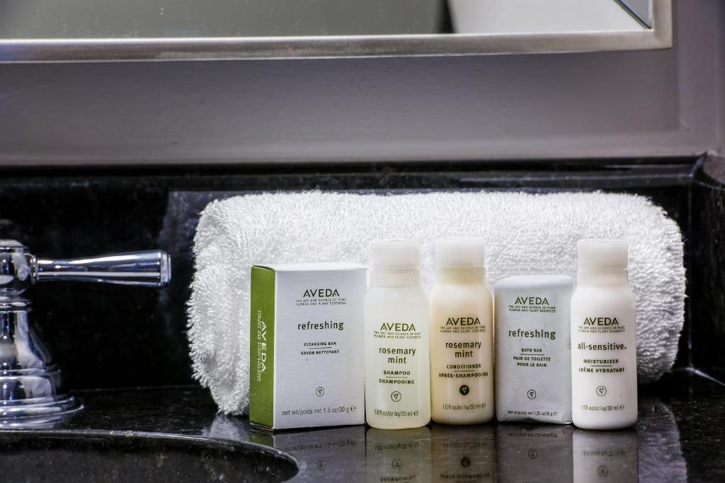 four bottles of moisturizers sitting on a bathroom sink at Hotel Indigo Dallas Downtown, an IHG Hotel in Dallas