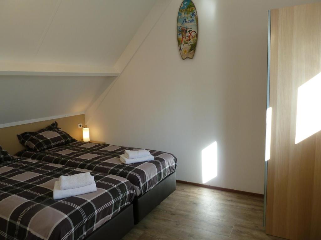 een slaapkamer met 2 bedden en een klok aan de muur bij Vacation home Zwaantje #DKR2 in Callantsoog