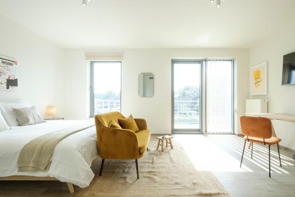 1 dormitorio blanco con 1 cama y 1 silla en Nice studios fully equipped near SHAPE area en Mons