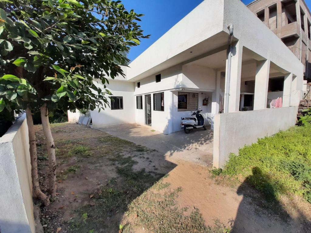 un edificio blanco con un árbol delante en Beds & Boys Hostel, en Nagpur