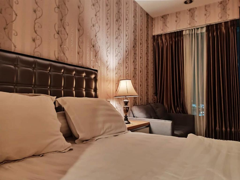 Apartemen grand kamala lagoon by 21 Room في بيكاسي: غرفة نوم بسرير واريكة ومصباح