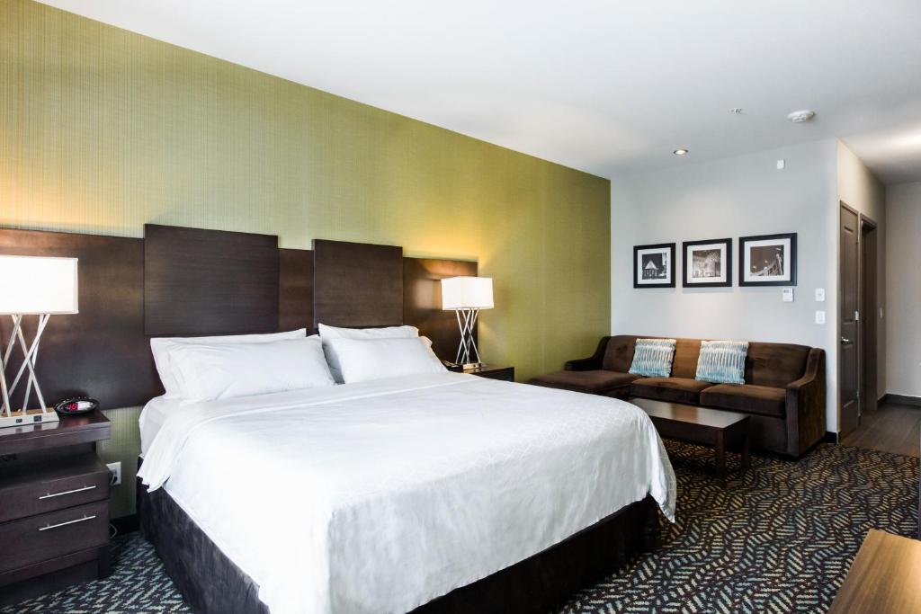 a hotel room with a large bed and a couch at Holiday Inn Express & Suites Spruce Grove - Stony Plain by IHG in Spruce Grove