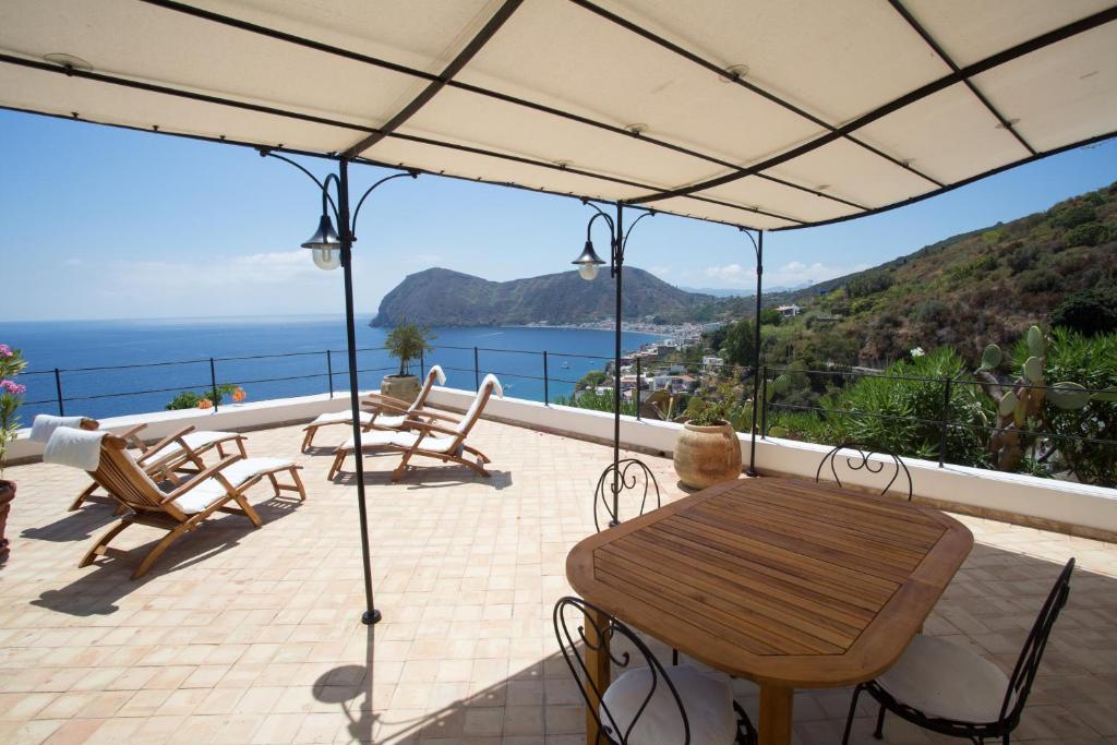 een patio met een tafel en stoelen en de oceaan bij 2 bedrooms house at Lipari 300 m away from the beach with sea view furnished terrace and wifi in Lipari