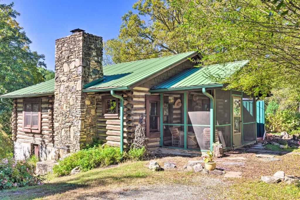 eine Blockhütte mit einem Kamin und einem grünen Dach in der Unterkunft Rustic-Yet-Cozy Cabin with Patio, 12 Mi to Asheville in Arden