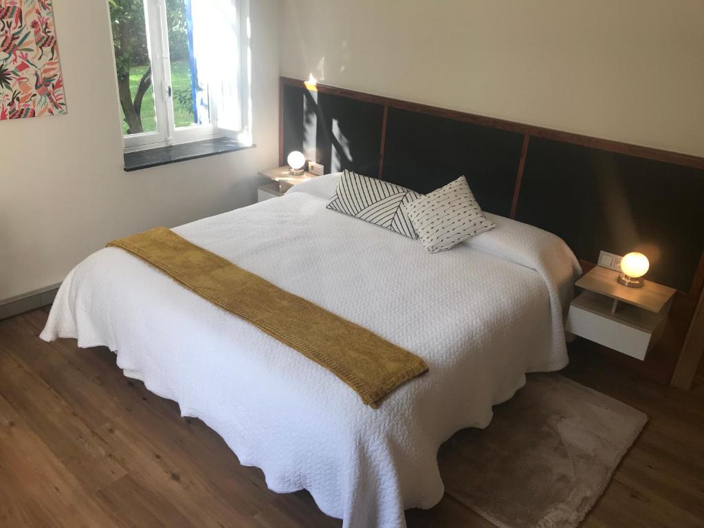 1 dormitorio con 1 cama blanca grande y 2 lámparas en Suites Mendibil Irun con parking gratuito dentro de la propiedad, en Irún