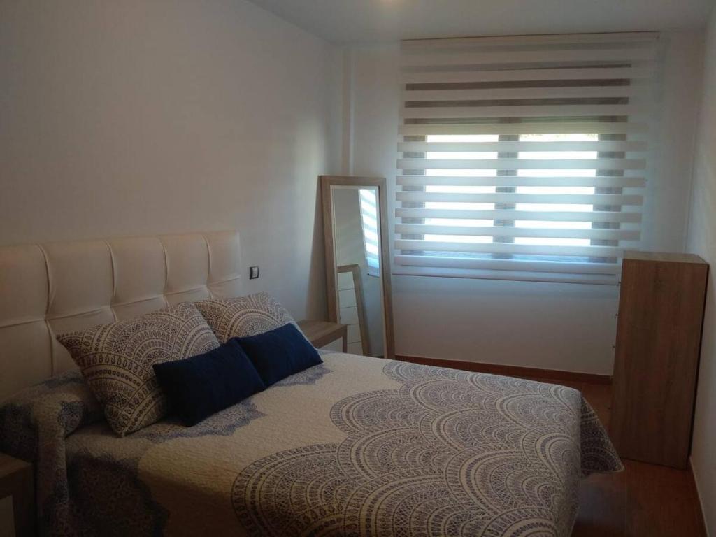 a bedroom with a bed and a window with blinds at Apartamento Muiño Bueu in Bueu