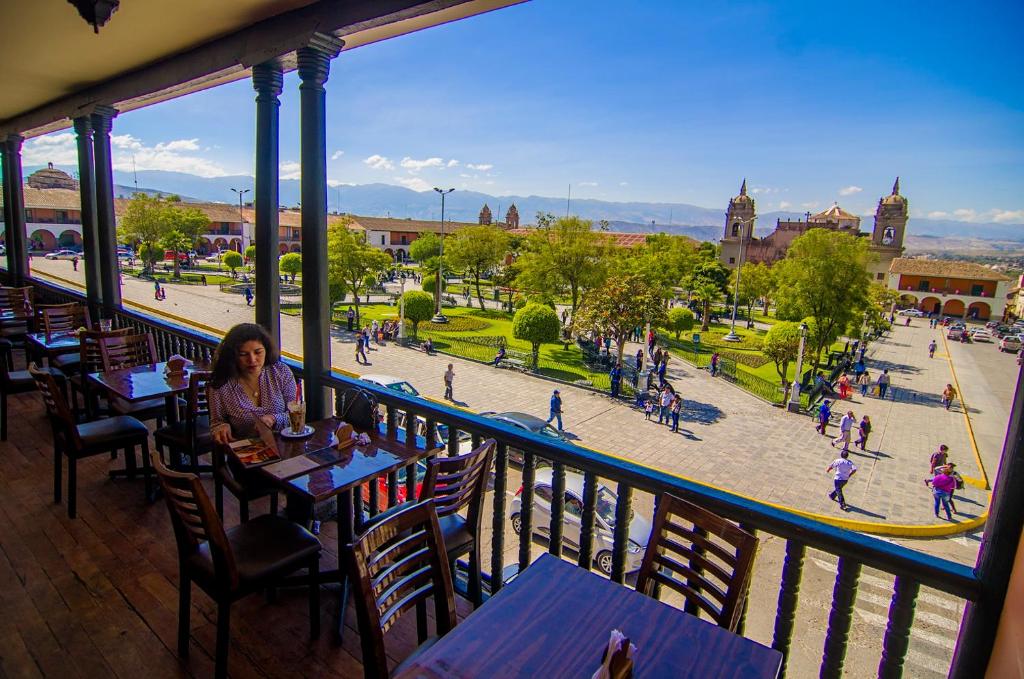 a woman sitting at a table in a restaurant with a view of a plaza at ViaVia Cafe Ayacucho in Ayacucho