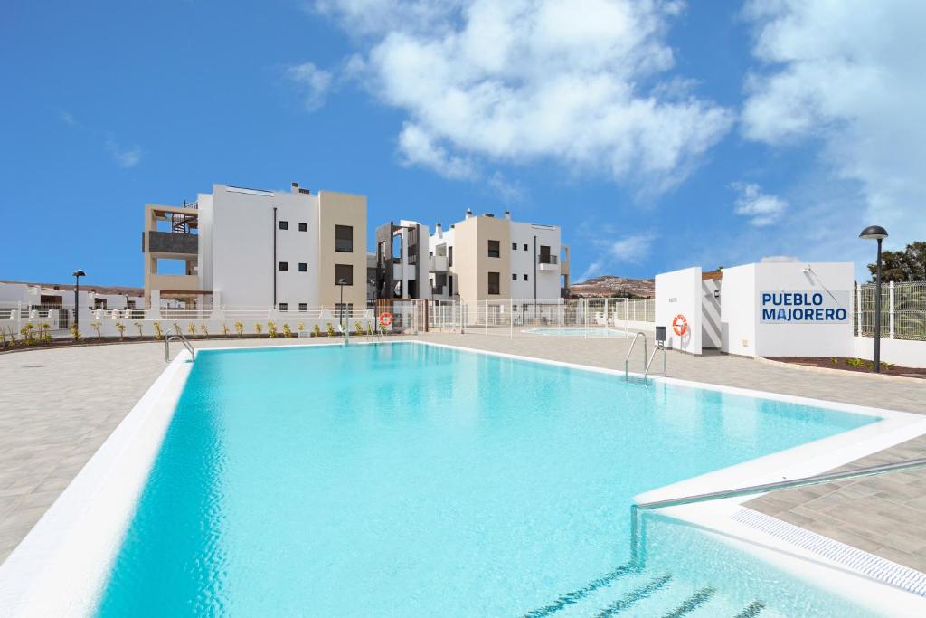 a large blue swimming pool with buildings in the background at HomeForGuest Flat with large terrace in modern residential complex with swimming pool in Caleta De Fuste