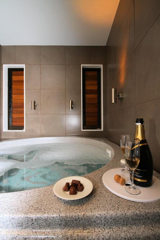 a hot tub with two plates of food and wine glasses at Bentleys Motor Inn in Palmerston North