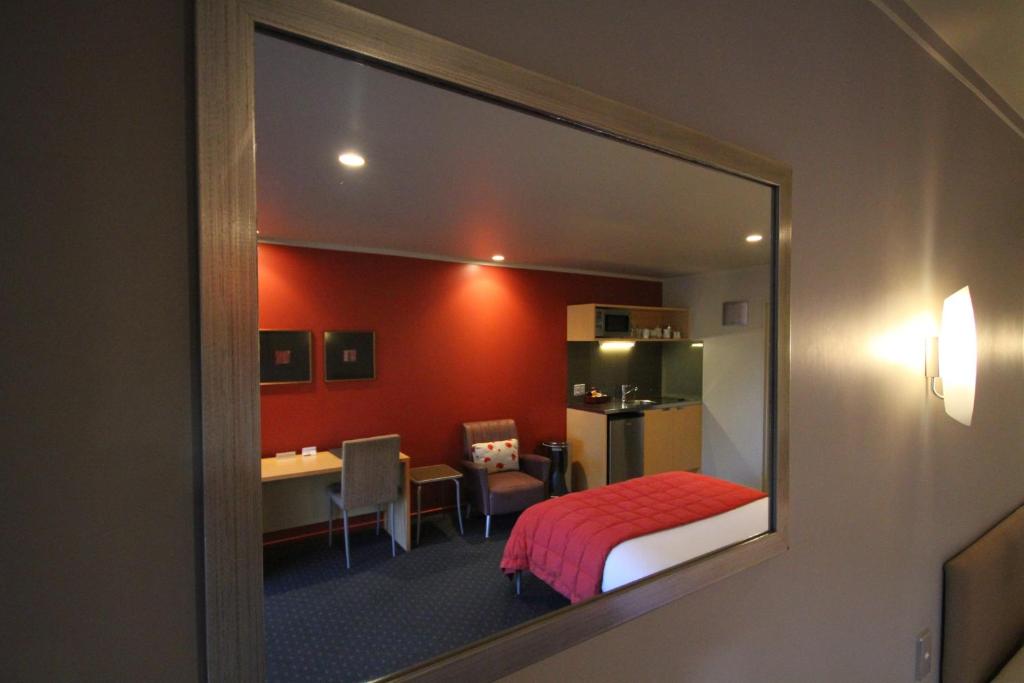 a room with a bedroom with a bed and a desk at Bentleys Motor Inn in Palmerston North
