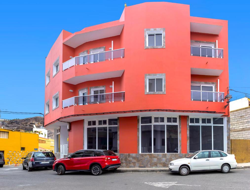 un edificio rojo con coches estacionados frente a él en Apartamentos La Aldea Suites, en San Nicolás
