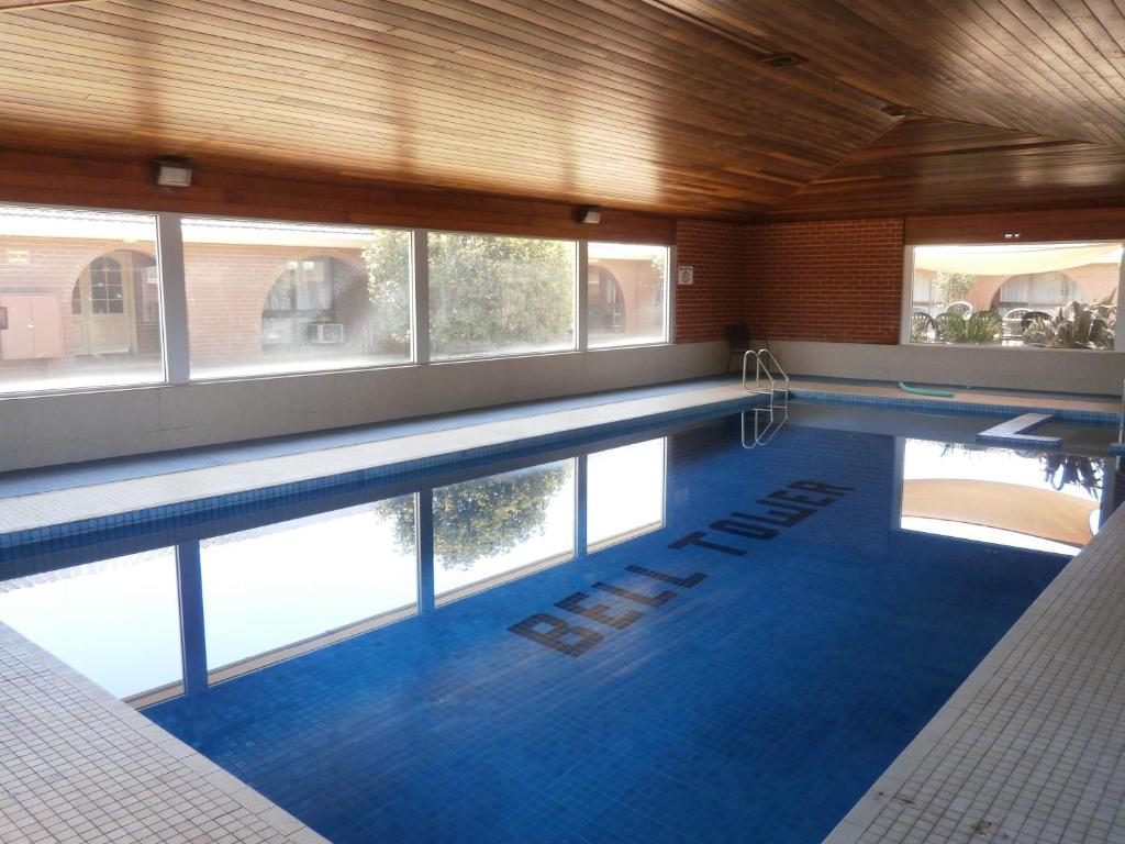 a large swimming pool with blue tiles in a building at Bell Tower Inn in Ballarat