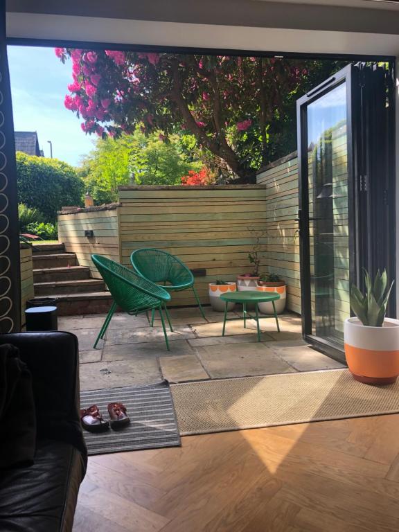 a patio with a green chair and a table at Chorlton Garden Rooms. Relax, work, stay and play. in Manchester