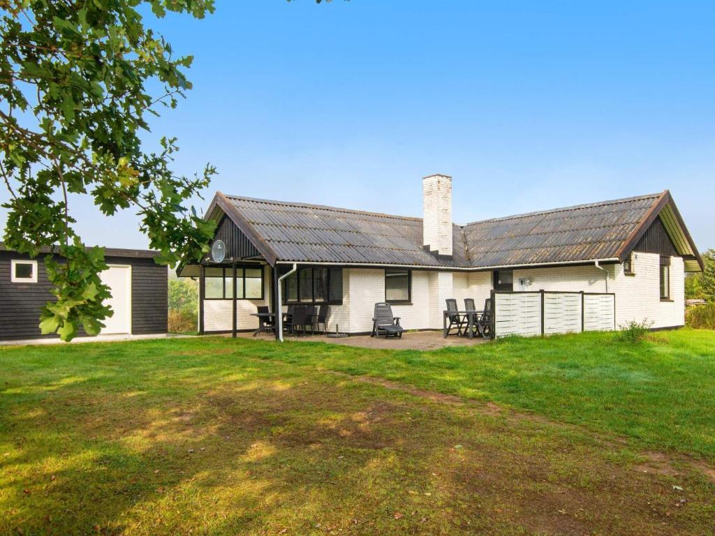 een wit huis met een metalen dak en een tuin bij 7 person holiday home in Knebel in Knebel