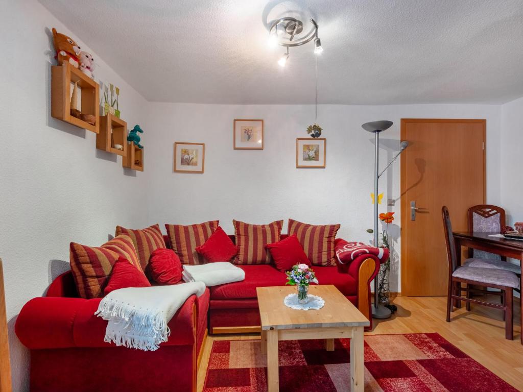 ein Wohnzimmer mit einem roten Sofa und einem Tisch in der Unterkunft Pleasant Apartment in Bad Doberan near the Sea in Bad Doberan
