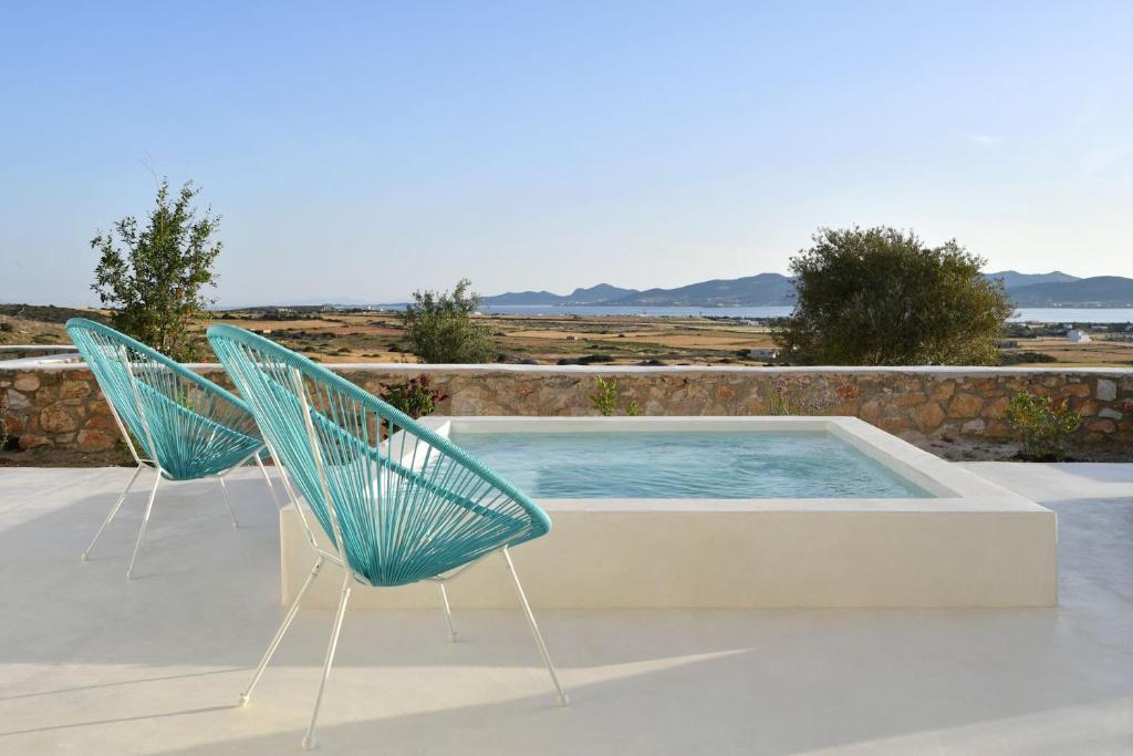 two chairs sitting next to a swimming pool at Luxury Paros Villa Villa Aethra Beautiful Serene Glisidia in Kampos Paros