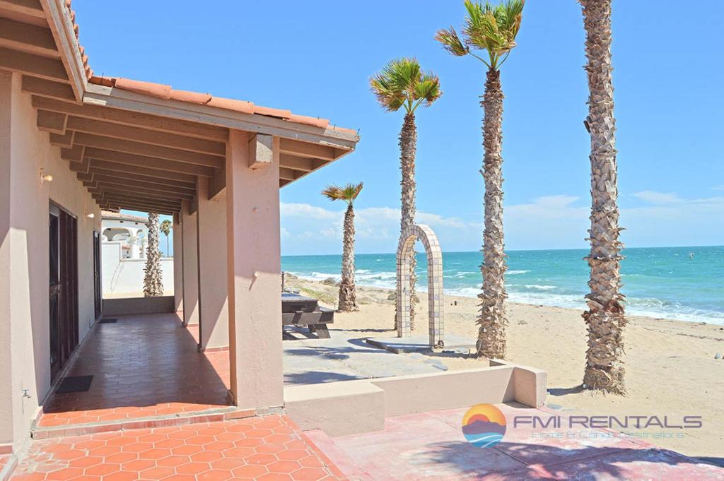a house on the beach with palm trees and the ocean at Casa Chapman by FMI Rentals in Puerto Peñasco
