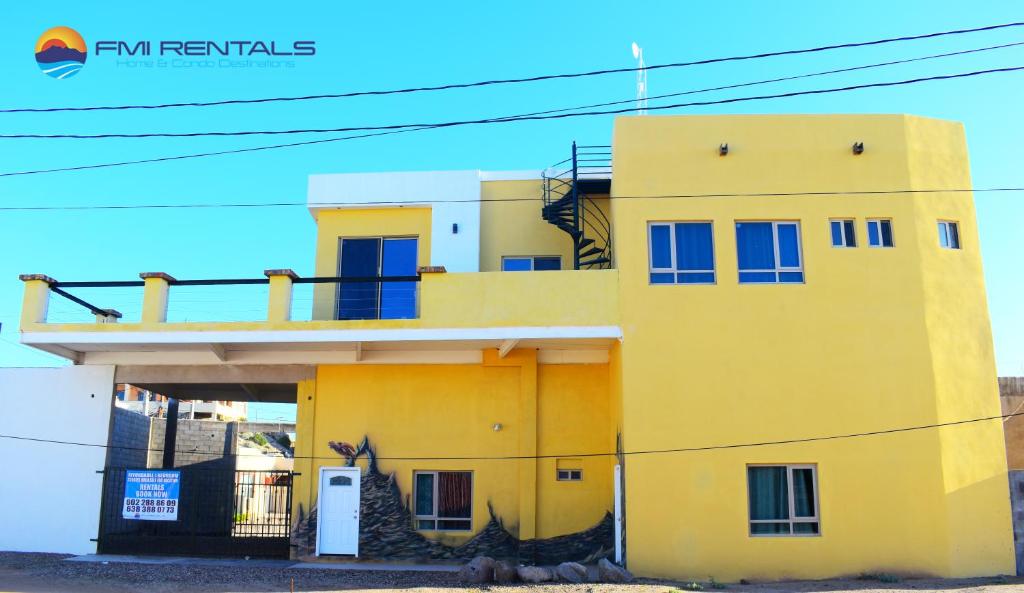 un edificio amarillo con ventanas azules en la parte superior en Turtle Studio en Puerto Peñasco