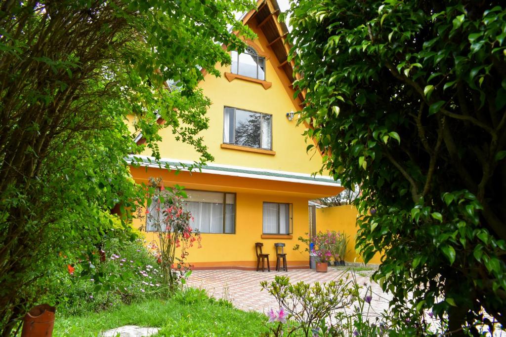 uma casa amarela com duas cadeiras à frente em Casa Iris em Chía