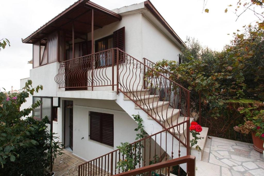 a white house with a staircase in front of it at Apartments Zeljko - with garden in Seget Vranjica