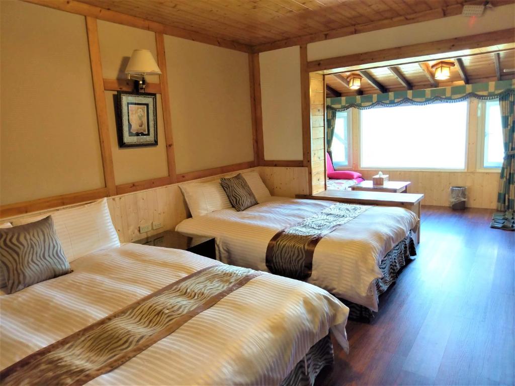 a room with two beds and a table and a window at Shiyai Taoyuan in Ren&#39;ai