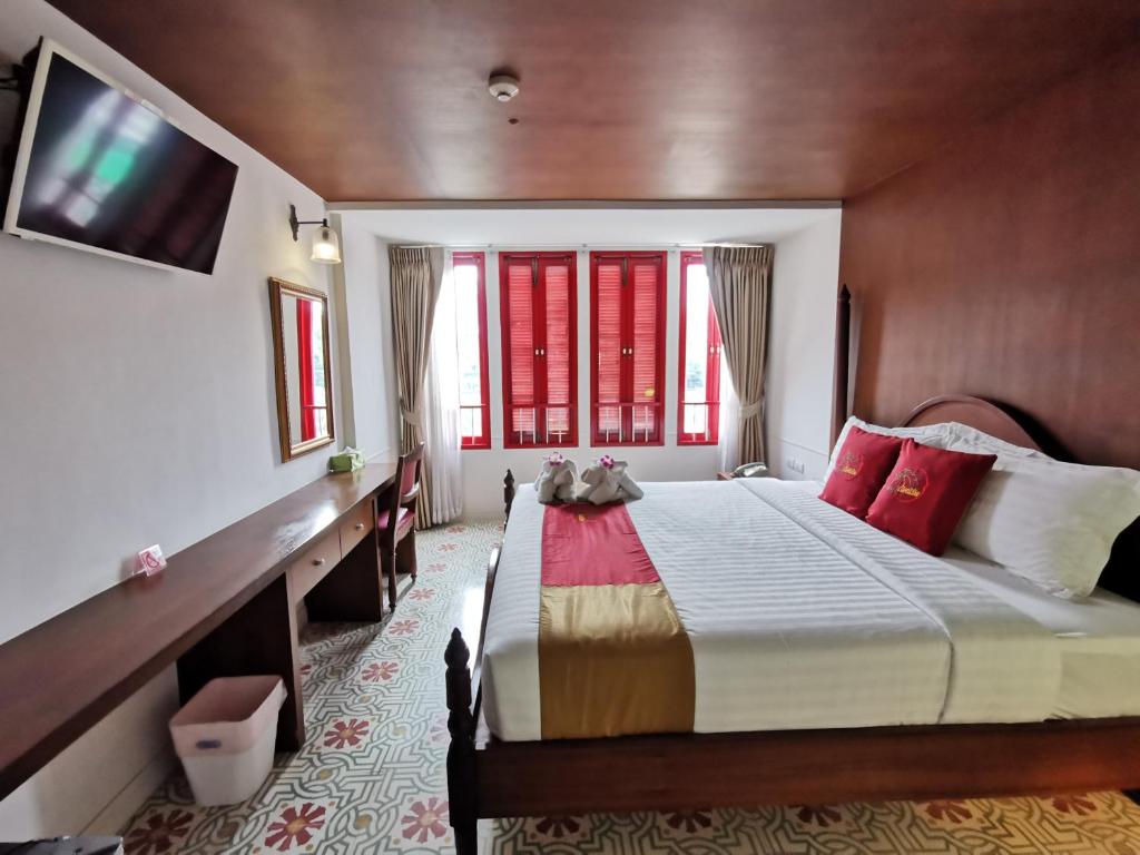 a bedroom with a large bed with red windows at Lertnimit Boutique Hotel in Hua Hin