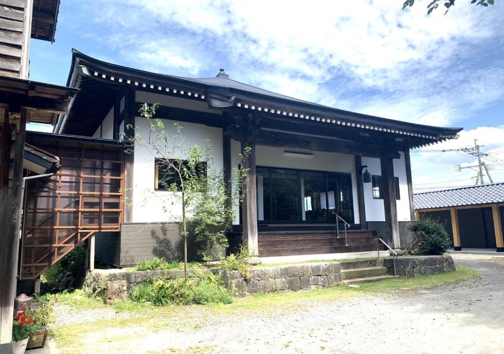 une maison avec une terrasse couverte et des escaliers en face de celle-ci dans l'établissement Ryokoji Temple, à Minami Aso