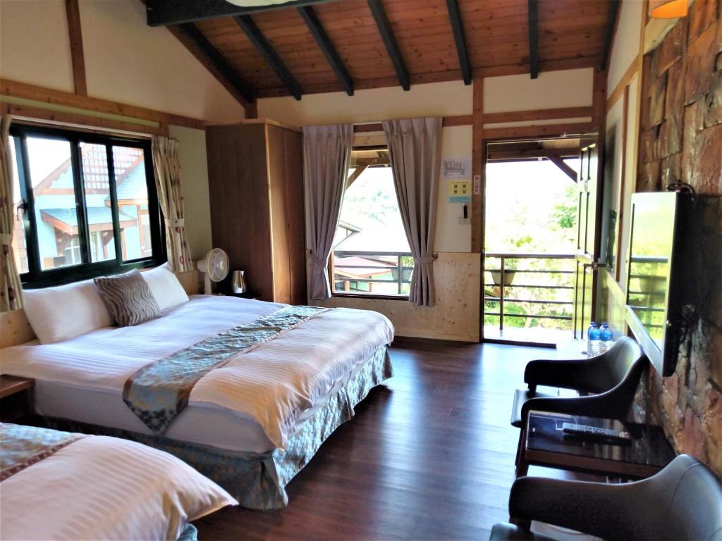 a bedroom with two beds and a chair and windows at Shiyai Taoyuan in Ren&#39;ai