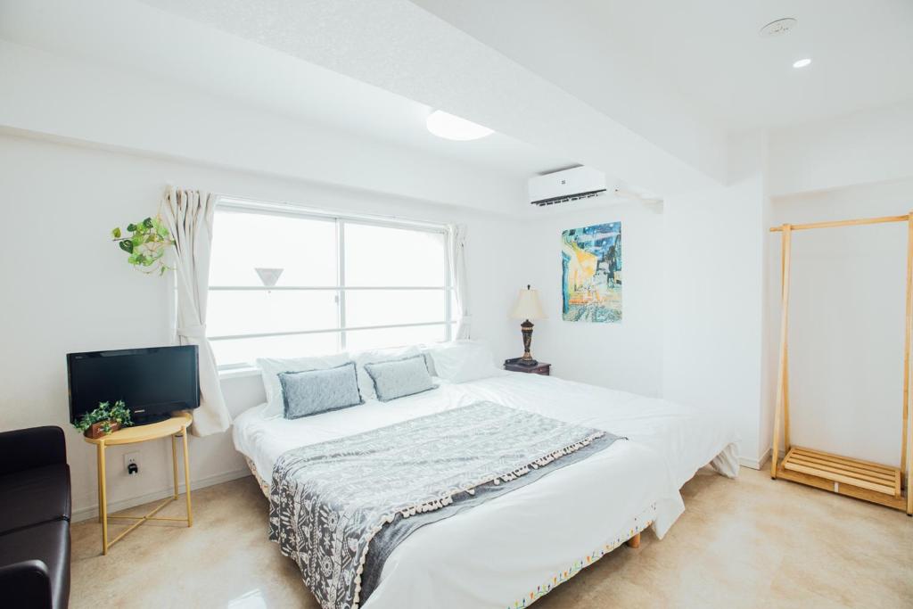 - une chambre blanche avec un grand lit et une fenêtre dans l'établissement 横浜元町, à Yokohama