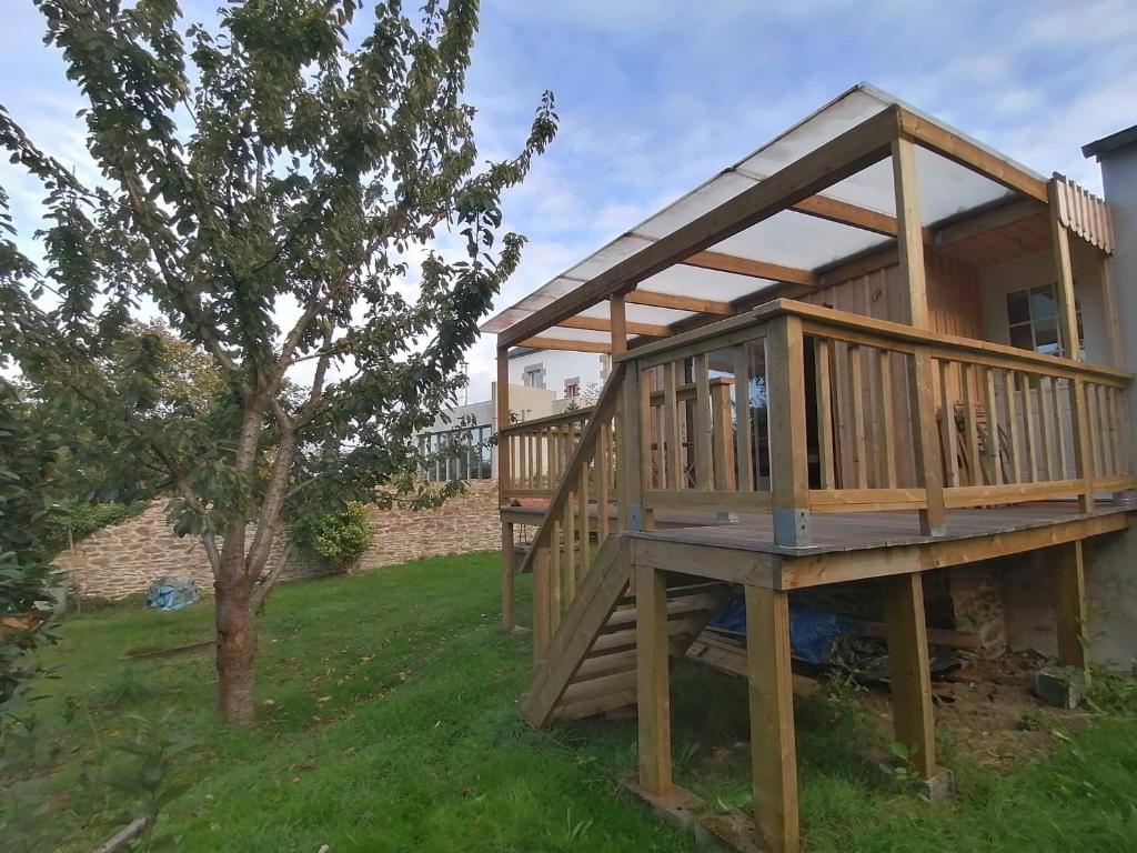 een groot houten terras met een boom in een tuin bij Tipergwendiou in Plougonvelin