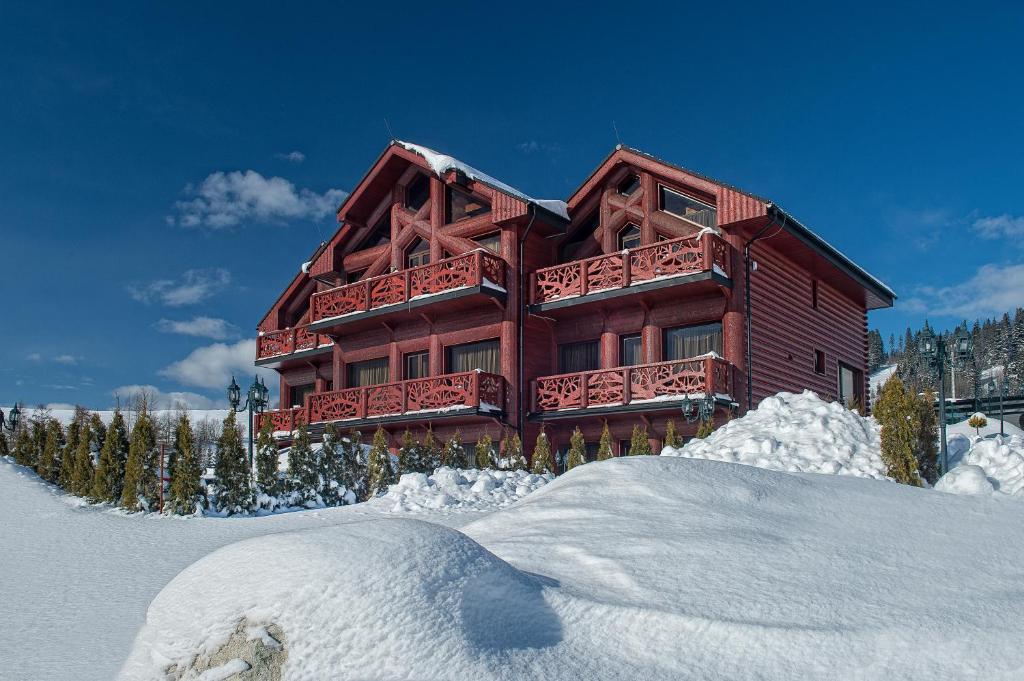 a large wooden house with snow in front of it at Mountain Resort Residences in Ždiar