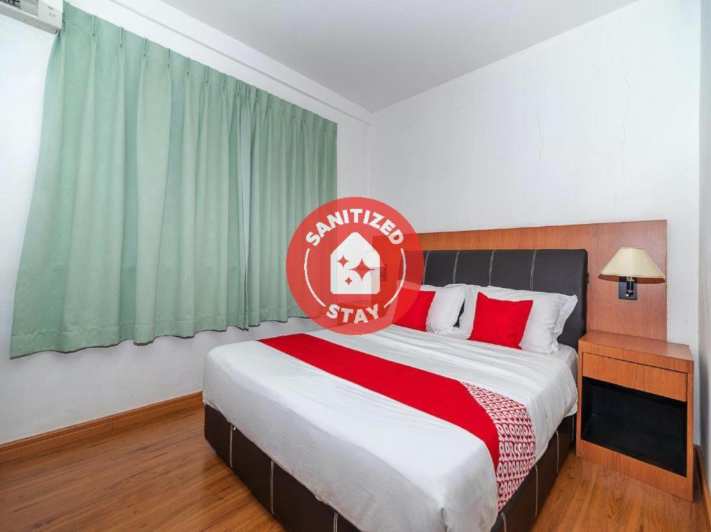 ein Schlafzimmer mit einem großen Bett mit einem roten Schild darauf in der Unterkunft OYO 90036 Eagle Wood Garden in Membakut