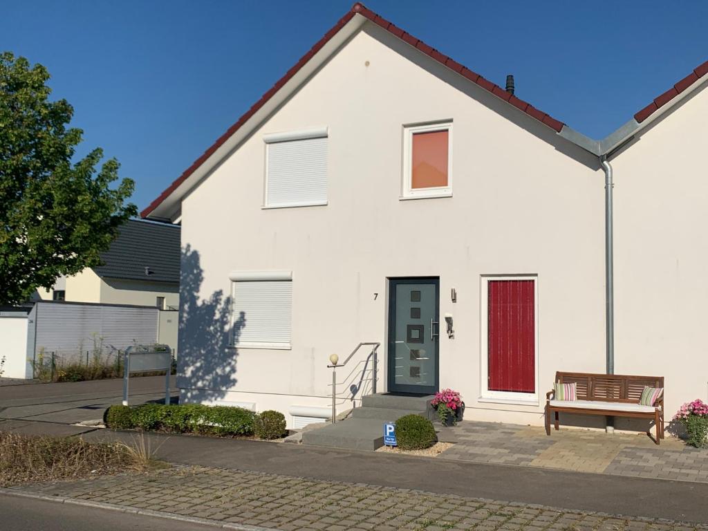 una casa blanca con una puerta roja y un banco en Ferienwohnungen Holder en Dettingen an der Erms