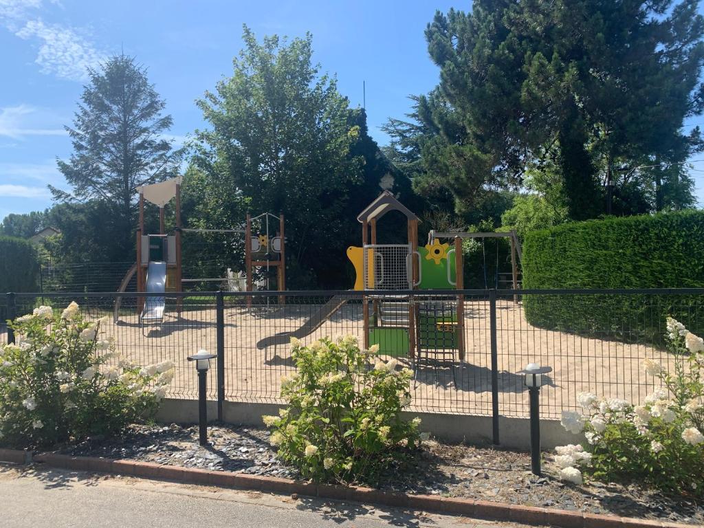 a playground in a park with a fence at Camping Pomme de Pin in Stella-Plage