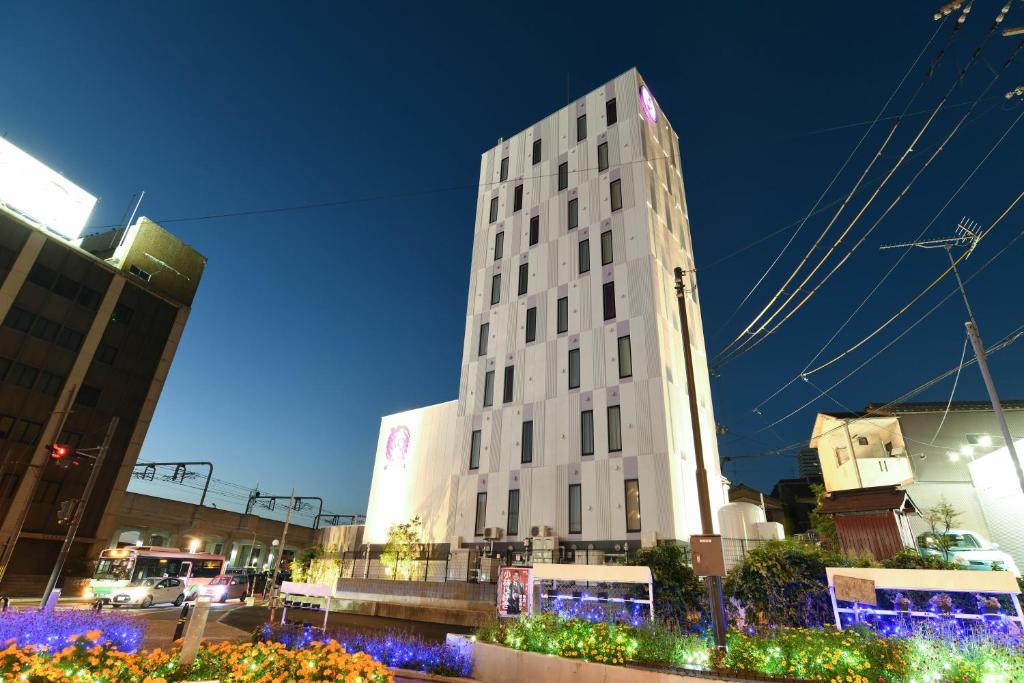 a tall white building in a city at night at Hotel Wisteria NARA in Nara