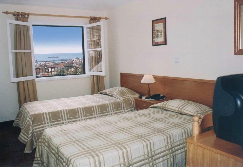 Cette chambre comprend 2 lits et une fenêtre. dans l'établissement Residencial Do Vale, à Funchal