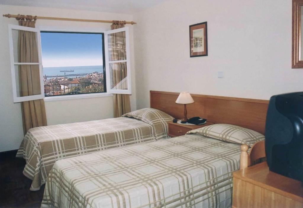 フンシャルにあるResidencial Do Valeのベッド2台と窓が備わるホテルルームです。