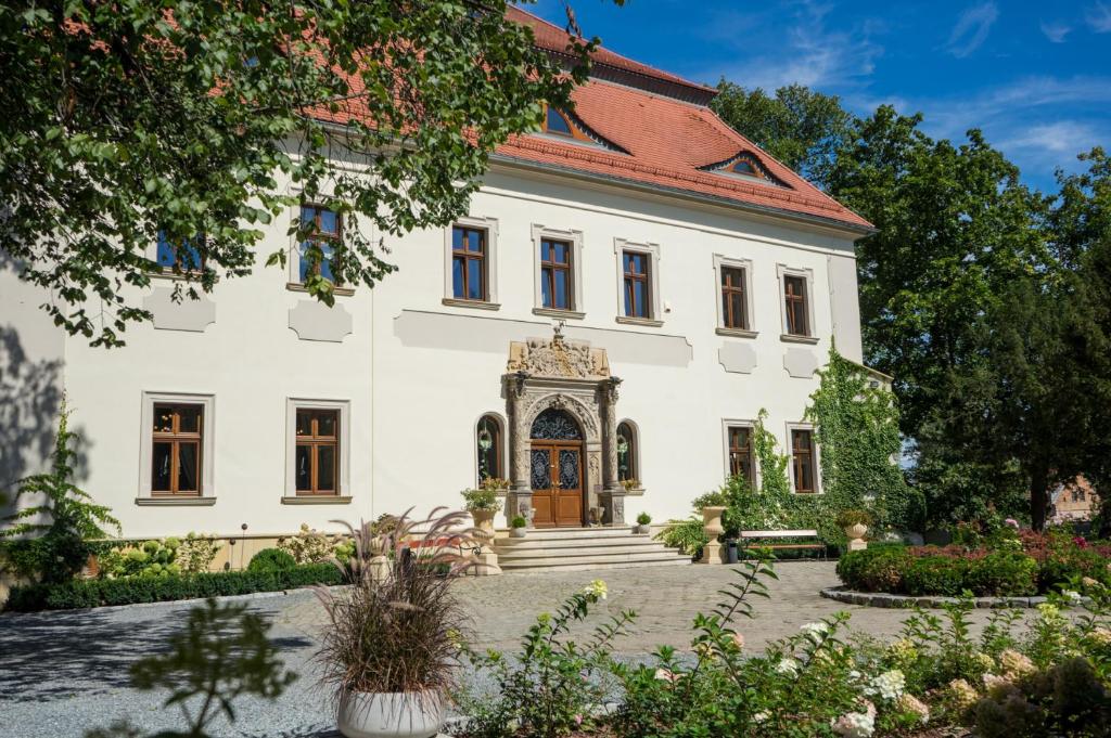 a large white house with a gate in front of it at Pałac Mojęcice in Mojęcice