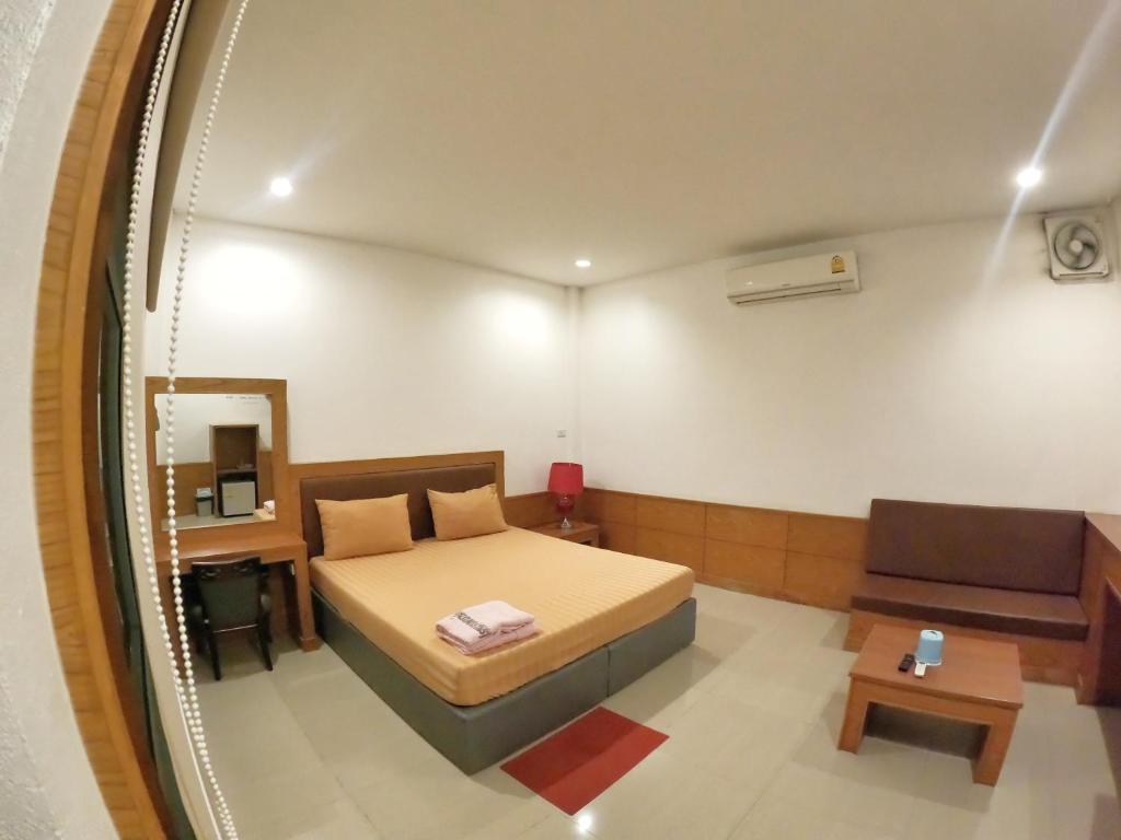 北碧Paradise Hotel โรงแรมพาราไดซ์ท่าม่วง的卧室里有一张床、一张沙发和一面镜子