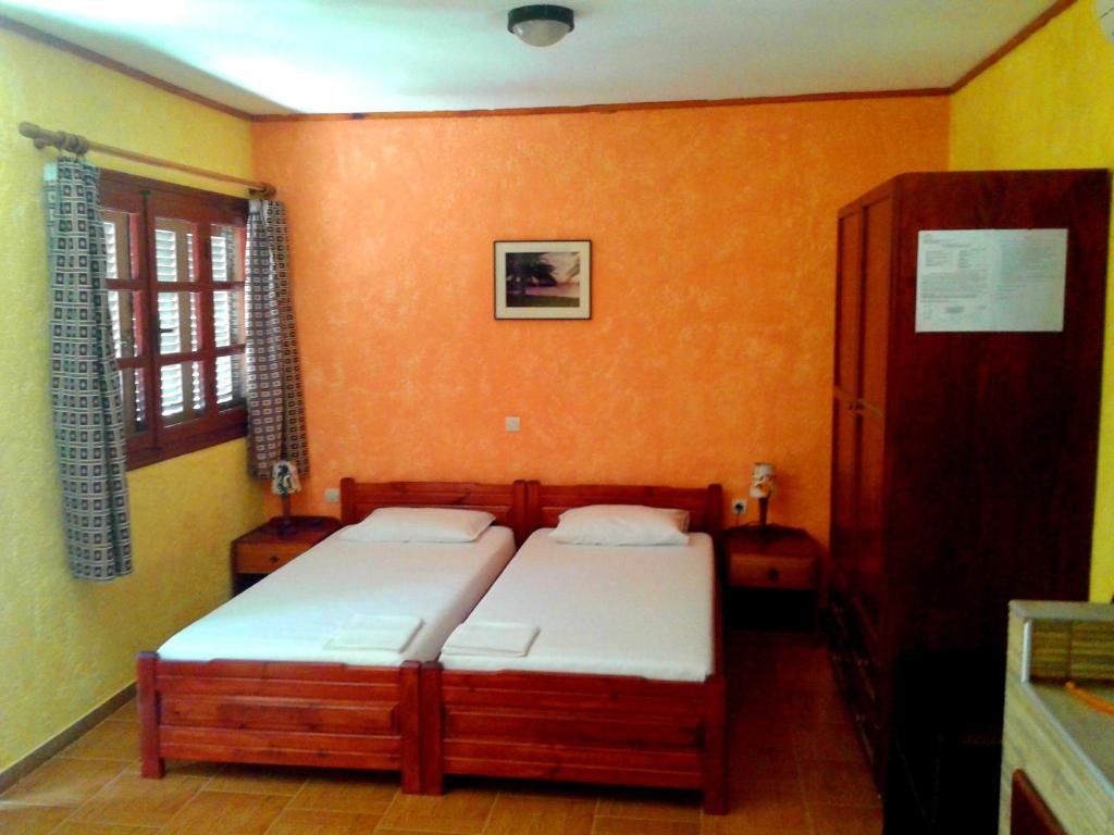 two beds in a room with orange walls at Sunrise Apartments in Palekastron