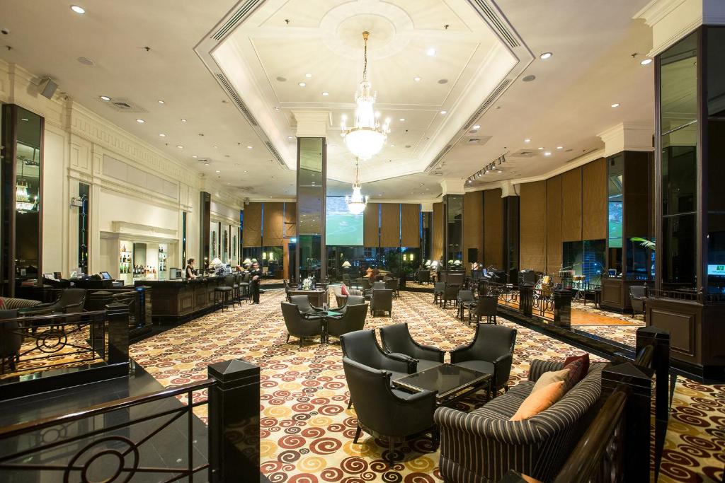 A formal lounge lobby has clustered seating, chandeliers, patterned carpet and a long bar or service counter.