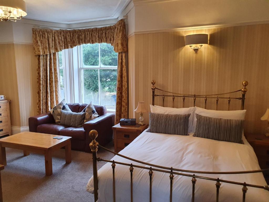 a bedroom with a bed and a couch and a window at Strathmore Guest House in Keswick