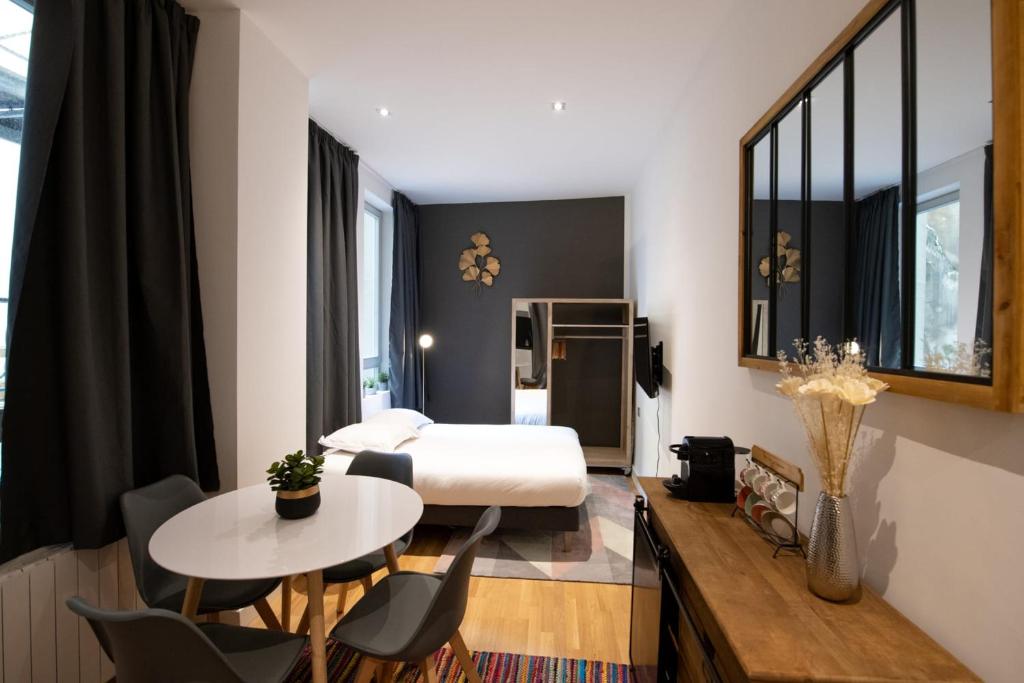 Habitación de hotel con cama, mesa y sillas en Le St Germain - Pétillant studio décoré avec goût en centre-ville, en Lyon