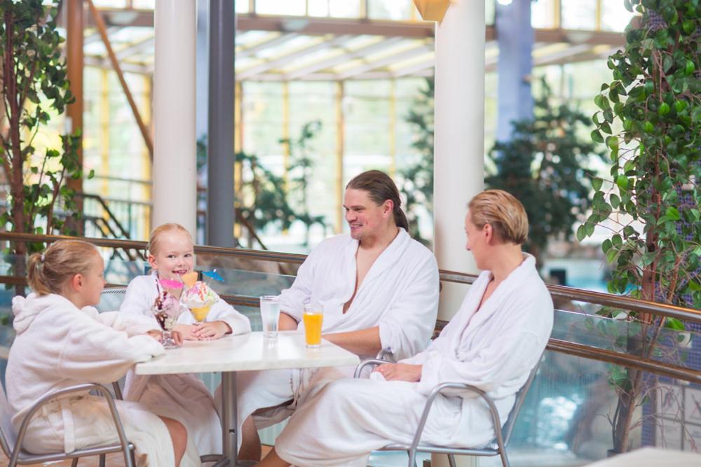 grupa ludzi siedzących przy stole z dzieckiem w obiekcie Imatran Kylpylä Spa Apartments w mieście Imatra
