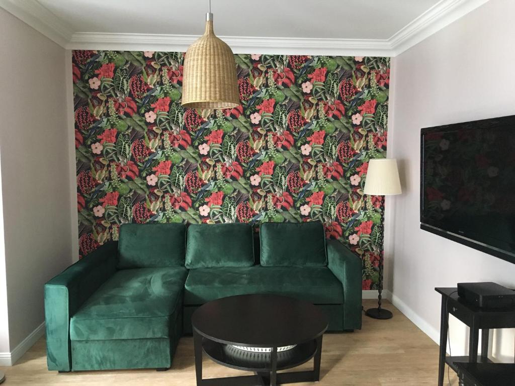 a living room with a green couch and a floral wallpaper at Kapart Apartament Szafarnia in Gdańsk