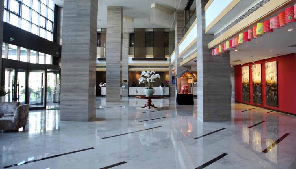 um lobby de um edifício com uma planta no meio em Holiday Inn Beijing Deshengmen, an IHG Hotel em Pequim
