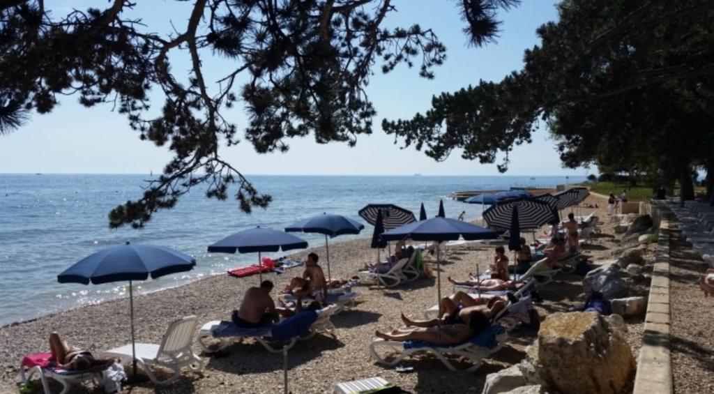 eine Gruppe von Menschen, die am Strand mit Sonnenschirmen sitzen in der Unterkunft Residence Lavanda in Umag