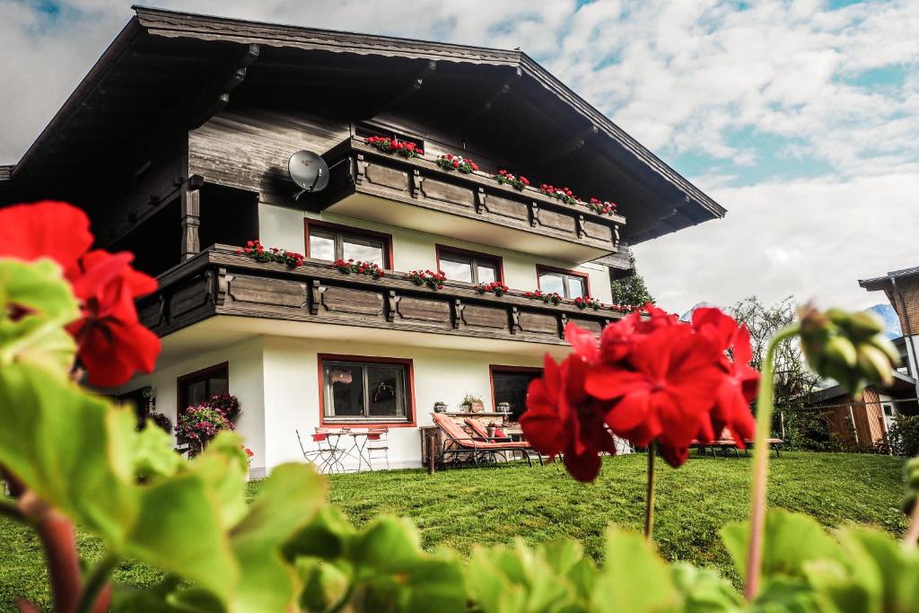 een huis met rode bloemen ervoor bij Au Pension in Söll